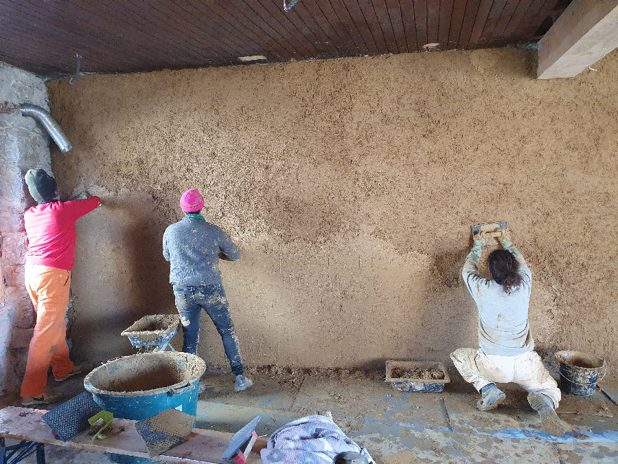 Avec la cliente et une amie à elle nous sommes prises en photo de dos en train d'appliquer du corps d'enduit sur le mur
