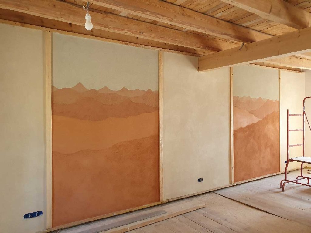 Fresque réalisé avec des enduits en terre de différentes couleur et représentant un paysage de montagne typique de Haute-Loire