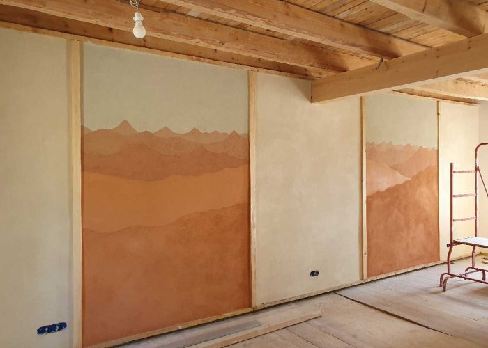 Fresque réalisé avec des enduits en terre de différentes couleur et représentant un paysage de montagne typique de Haute-Loire